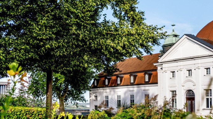 A historic building with a red roof and white walls, surrounded by green trees and plants, under a clear blue sky., &copy; DLA Marbach (Anja Bleeser)
