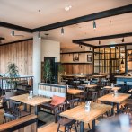 Modernes Brauhaus mit Holzmöbeln, Bar und Pflanzen. Gemütliche Atmosphäre mit Holzwänden und stilvoller Beleuchtung., © Andreas Engelhard - Engelhard Photography