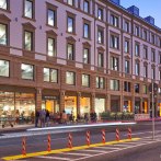 Office building at dusk, illuminated windows, people in front of the entrance. Modern architecture with a classic fa&ccedil;ade., &copy; Design Offices