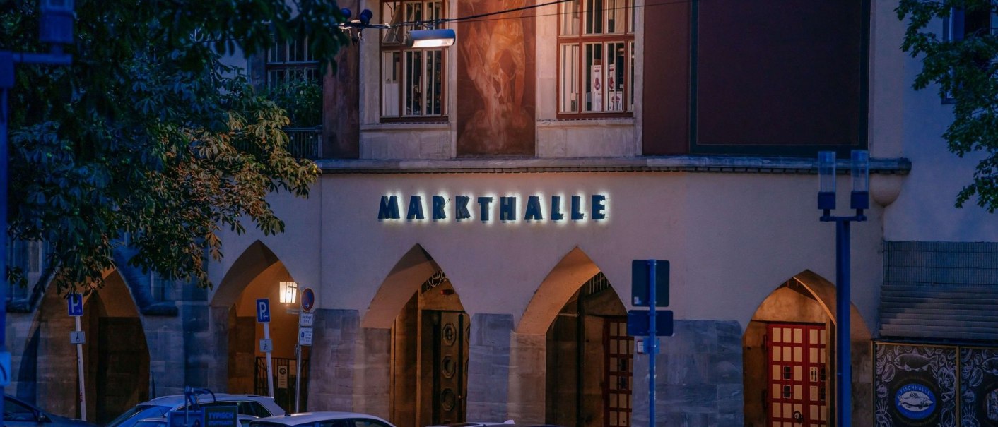 Eingang zur Markthalle bei Nacht, beleuchtetes Schild und B&ouml;gen, umgeben von B&auml;umen und Stra&szlig;enschildern., &copy; Thomas Niederm&uuml;ller