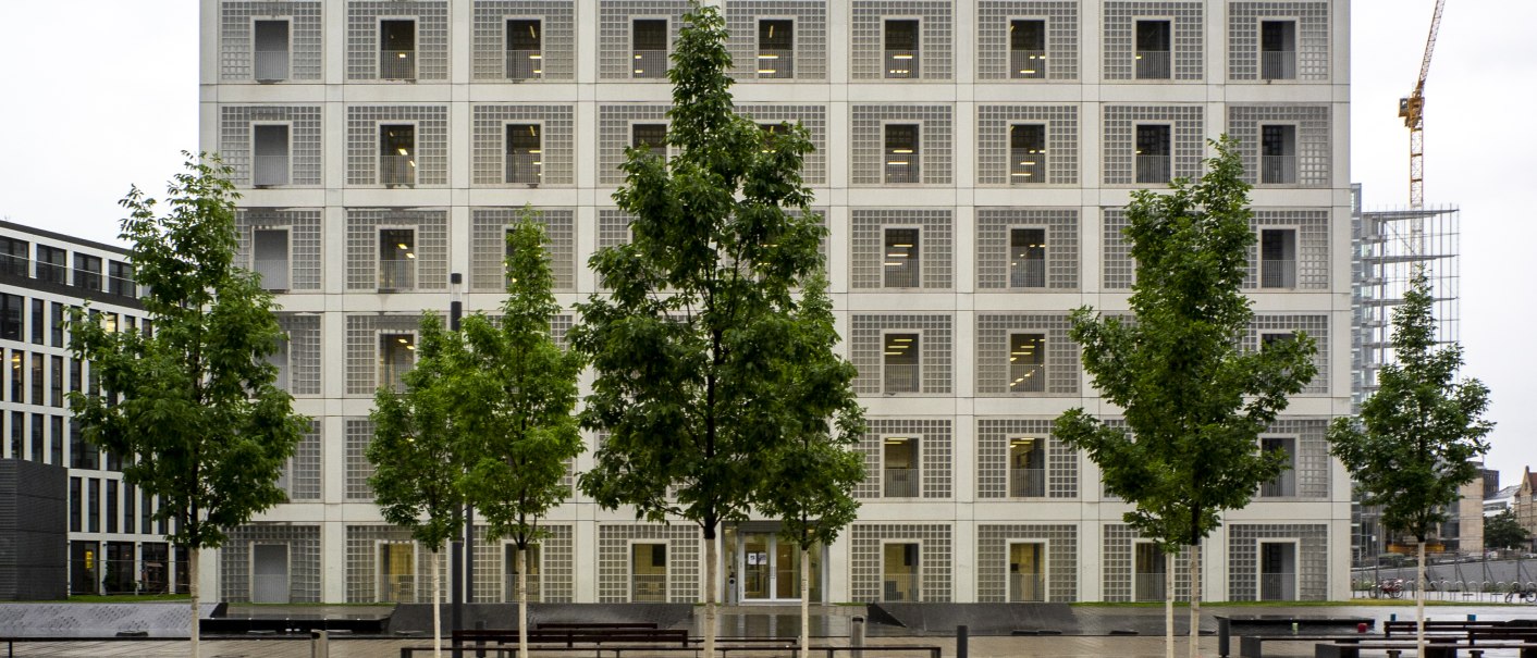 Die Stadtbibliothek Stuttgart mit ihrer symmetrischen, modernen Fassade und B&auml;umen im Vordergrund an einem bew&ouml;lkten Tag., &copy; Frank Hoerner