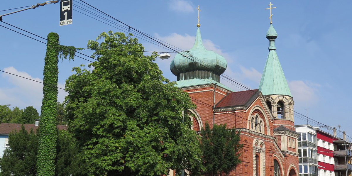 Eine russische Kirche mit markantem Zwiebelturm und grüner Kuppel, umgeben von Bäumen und Stromleitungen, bei klarem Himmel., © Stuttgart-Marketing GmbH