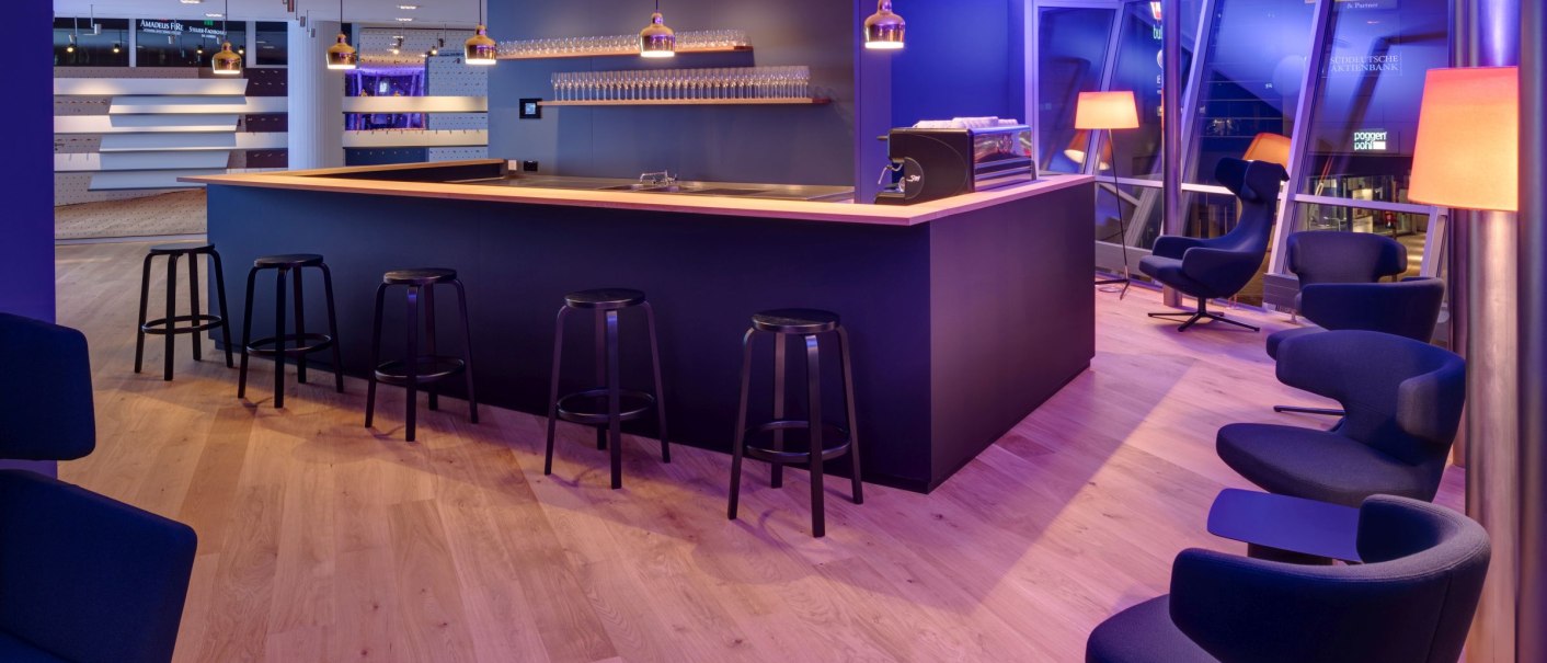 Modern bar area with blue lighting, wooden floor, black stools and comfortable armchairs. Elegant atmosphere with stylish lamps., © www.wilhelmy-fotografie.de