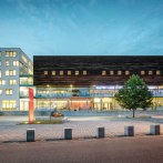 Moderne Architektur des SpOrt Stuttgart bei Dämmerung, mit beleuchteten Fenstern und einem Baum im Vordergrund., © Josh von Staudach