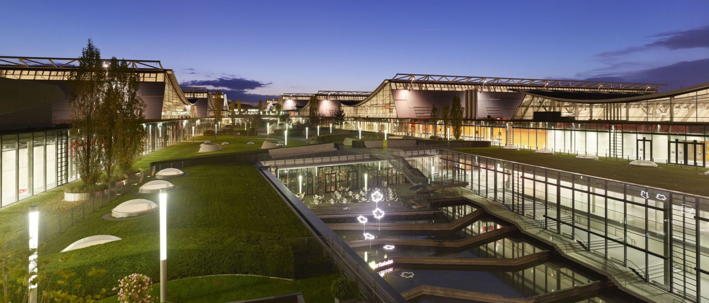 Night shot of Messe Stuttgart with illuminated buildings, green areas and water basins. Modern architecture under a clear evening sky., &copy; Roland Halbe