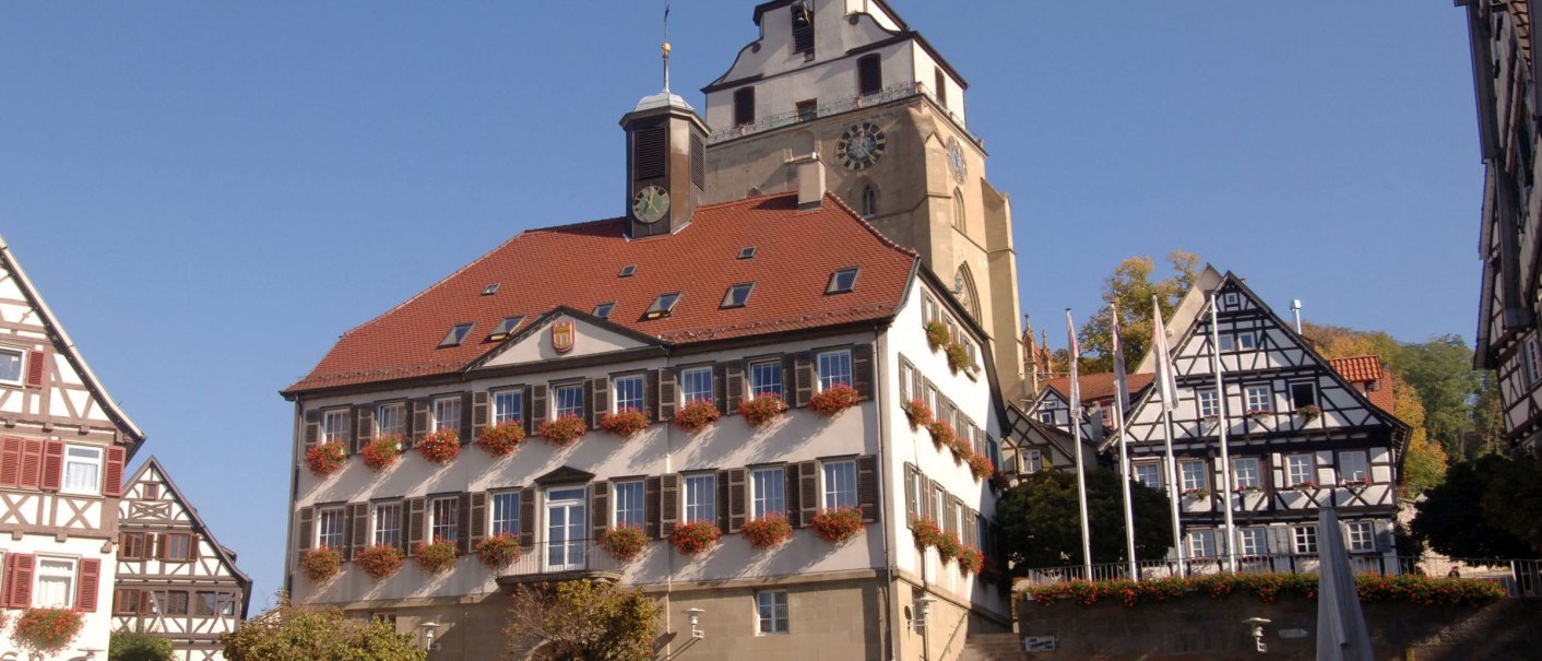 Marktplatz in Herrenberg mit Fachwerkhäusern, einem Turm und blühenden Blumen an den Fenstern bei sonnigem Wetter., © Stadt Herrenberg Marktplatz in Herrenberg mit Fachwerkhäusern, einem Turm und blühenden Blumen an den Fenstern bei sonnigem Wetter., © Stadt Herrenberg