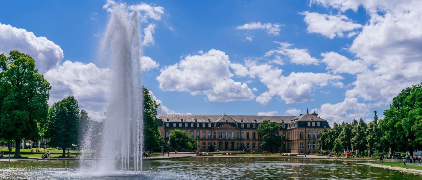 Das Bild zeigt das Neue Schloss in Stuttgart mit einem großen Springbrunnen im Vordergrund und dem Eckensee. Der Himmel ist blau mit weißen Wolken., © Thomas Niedermüller Das Bild zeigt das Neue Schloss in Stuttgart mit einem großen Springbrunnen im Vordergrund und dem Eckensee. Der Himmel ist blau mit weißen Wolken., © Thomas Niedermüller