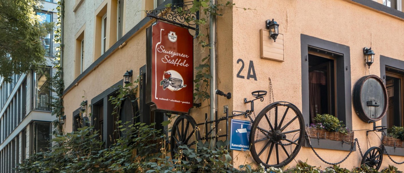 Building with the sign 'Stuttgarter St&auml;ffele', decorated with wagon wheels and plants. The fa&ccedil;ade is beige with black window frames., &copy; SMG Stuttgart Marketing GmbH - Sarah Schmid