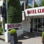 Eingang des Hotel Gloria mit großem Schild und gepflegten Pflanzen. Moderne Glasfront und dekorative Sträucher umrahmen den Eingang., © Hotel Gloria