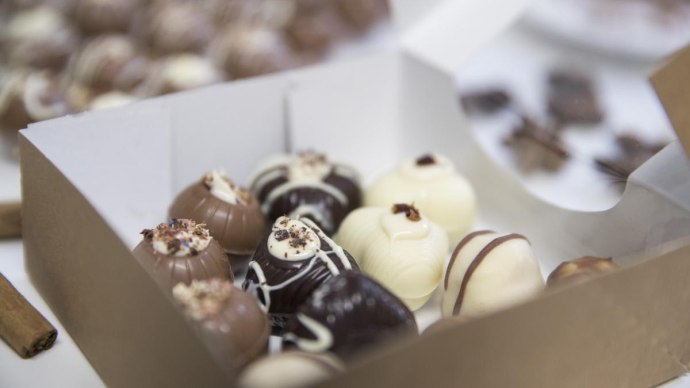 Eine Schachtel mit handgemachten Pralinen in verschiedenen Schokoladensorten, dekoriert mit Streuseln und Mustern., © hoponopo GmbH Eine Schachtel mit handgemachten Pralinen in verschiedenen Schokoladensorten, dekoriert mit Streuseln und Mustern., © hoponopo GmbH