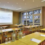 Tagungsraum im Amber Hotel Leonberg/Stuttgart mit Tischen, Stühlen, Wasserflaschen und einer Präsentationsleinwand., © DH STUDIO Dirk Holst