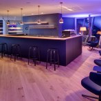 Modern bar area with blue lighting, wooden floor, black stools and comfortable armchairs. Elegant atmosphere with stylish lamps., &copy; www.wilhelmy-fotografie.de