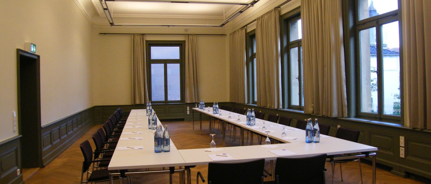 A meeting room with a U-shaped table, chairs, water bottles and notepads. Large windows with curtains and parquet flooring., © Forum Koenig-Karls-Bad A meeting room with a U-shaped table, chairs, water bottles and notepads. Large windows with curtains and parquet flooring., © Forum Koenig-Karls-Bad