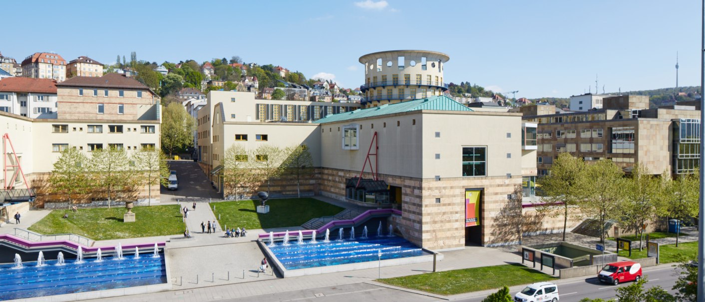 Das Haus der Geschichte Baden-Württemberg mit modernem Design, Springbrunnen und vorbeifahrenden Autos. Im Hintergrund sind Hügel und Gebäude zu sehen., © Bernd Eidenmueller