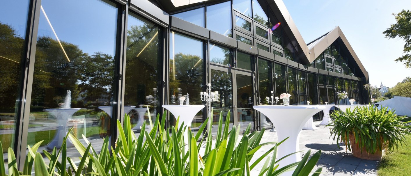Moderne Glasfassade der Filderhalle mit Stehtischen und Pflanzen im Vordergrund, bei sonnigem Wetter., © Guenter E. Bergmann - Photography