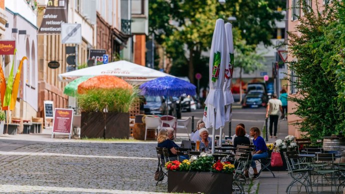 Straßenszene im Bohnenviertel mit Menschen, die an Tischen im Freien sitzen. Bunte Sonnenschirme und Pflanzen schmücken die Umgebung., © Thomas Niedermüller Straßenszene im Bohnenviertel mit Menschen, die an Tischen im Freien sitzen. Bunte Sonnenschirme und Pflanzen schmücken die Umgebung., © Thomas Niedermüller