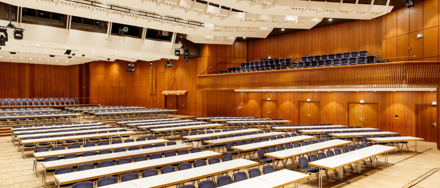 Großer Saal der Stadthalle Göppingen mit leeren Tischen und Stühlen, Holzwänden und moderner Beleuchtung., © Tobias Fröhner Photography