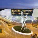 The Porsche Museum in Stuttgart at night, with modern architecture and illuminated streets. A sculpture of Porsche vehicles in the foreground., © Porsche AG