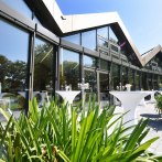 Modern glass façade of the Filderhalle with bar tables and plants in the foreground, in sunny weather., © Guenter E. Bergmann - Photography