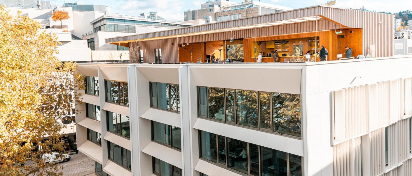 Modern fa&ccedil;ade of the House of Tourism with large glass windows and a terrace. People stroll along the paved square in front of it., &copy; SMG Stuttgart Marketing GmbH - Sarah Schmid