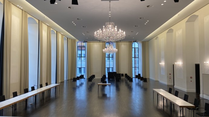 Elegant ballroom with chandeliers, long tables and chairs. High windows and bright walls create an inviting atmosphere., &copy; Kulturzentrum Prediger