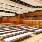 Large hall in the Stadthalle Göppingen with empty tables and chairs, wooden walls and modern lighting., © Tobias Fröhner Photography