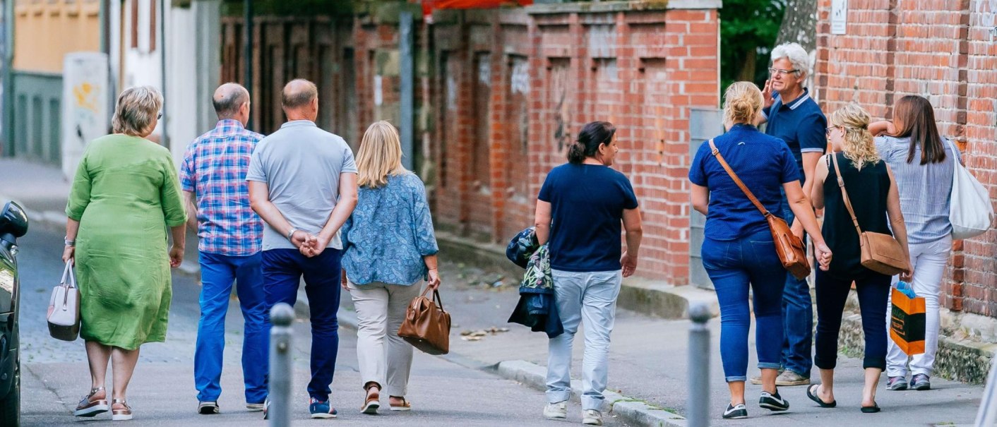 Gruppe von Menschen spaziert entlang einer Backsteinmauer in der Stadt., &copy; Thomas Niederm&uuml;ller