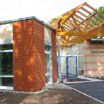 Moderner Eingangsbereich der Festhalle Althütte mit Glasfront und Holzdach. Die Fassade ist teils mit roten Kacheln verkleidet., © Gemeinde Althütte