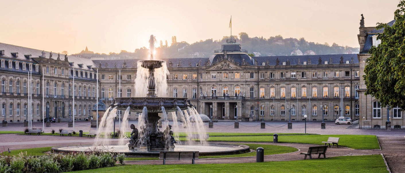 Das Neue Schloss Stuttgart bei Sonnenuntergang, mit einem großen Brunnen im Vordergrund und gepflegten Rasenflächen., © Stuttgart-Marketing GmbH Julian Herzog Das Neue Schloss Stuttgart bei Sonnenuntergang, mit einem großen Brunnen im Vordergrund und gepflegten Rasenflächen., © Stuttgart-Marketing GmbH Julian Herzog