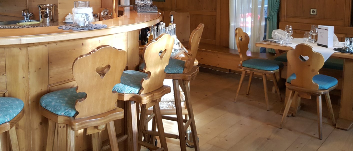 Gemütliches Restaurant mit Holzmöbeln, Bar und dekorativen Elementen. Holztische und -stühle mit blauen Polstern, helle Vorhänge und Wandbilder., © eriksonhotel_gf