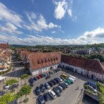 Aerial view of the Alte Kelter town hall in Besigheim, surrounded by traditional buildings and a parking lot with cars. Green hills in the background., © Stadthalle Alte Kelter Besigheim_Achim Mende