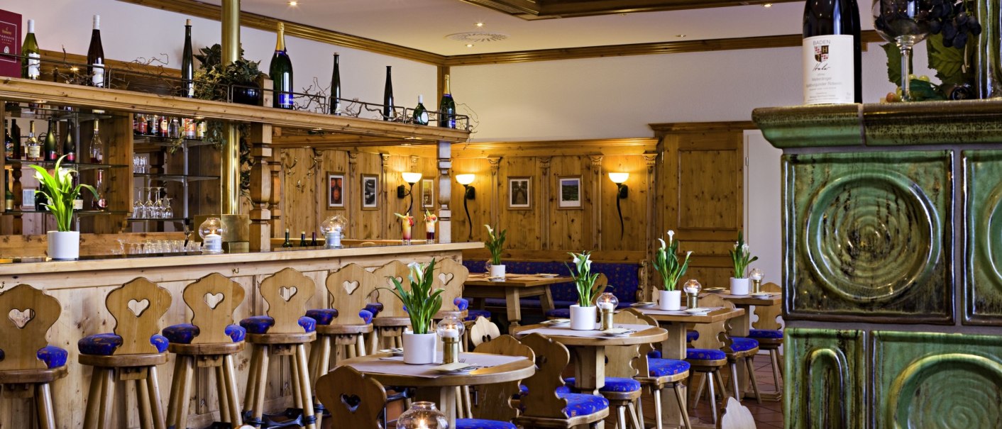Gem&uuml;tliches Restaurant mit Holzm&ouml;beln, blauen Polstern und gr&uuml;ner Kachelverkleidung. Bar mit Weinflaschen und dekorativen Pflanzen., &copy; Mercure Stuttgart Airport Messe