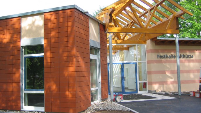 Moderner Eingangsbereich der Festhalle Alth&uuml;tte mit Glasfront und Holzdach. Die Fassade ist teils mit roten Kacheln verkleidet., &copy; Gemeinde Alth&uuml;tte