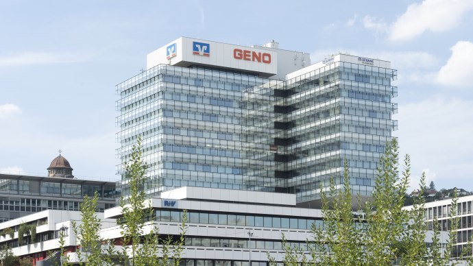 The GENO building with its modern glass fa&ccedil;ade and several storeys, surrounded by trees, under a blue sky., &copy; Geno-Haus