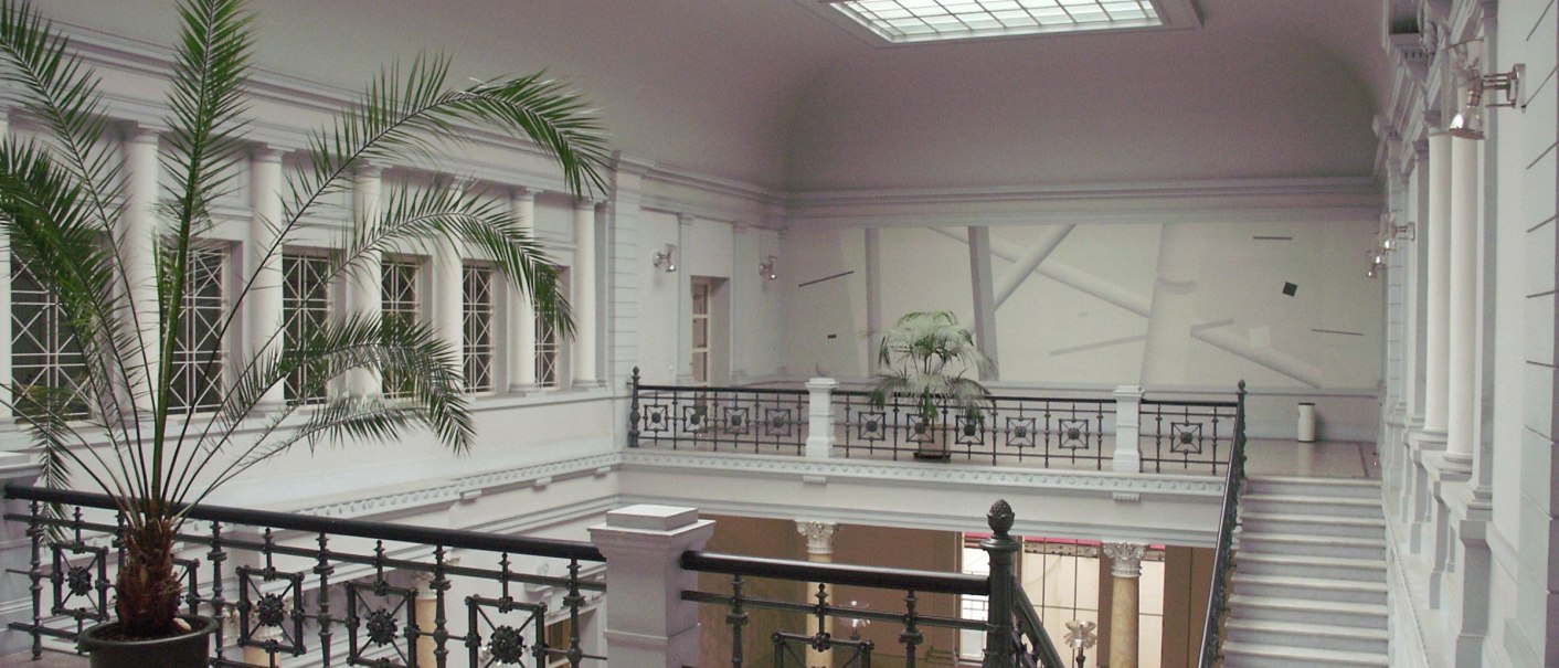 Innenansicht des Haus der Wirtschaft Baden-Württemberg mit eleganter Treppe, verzierten Geländern und Pflanzen unter einem großen Oberlicht., © Wirtschaftministerium