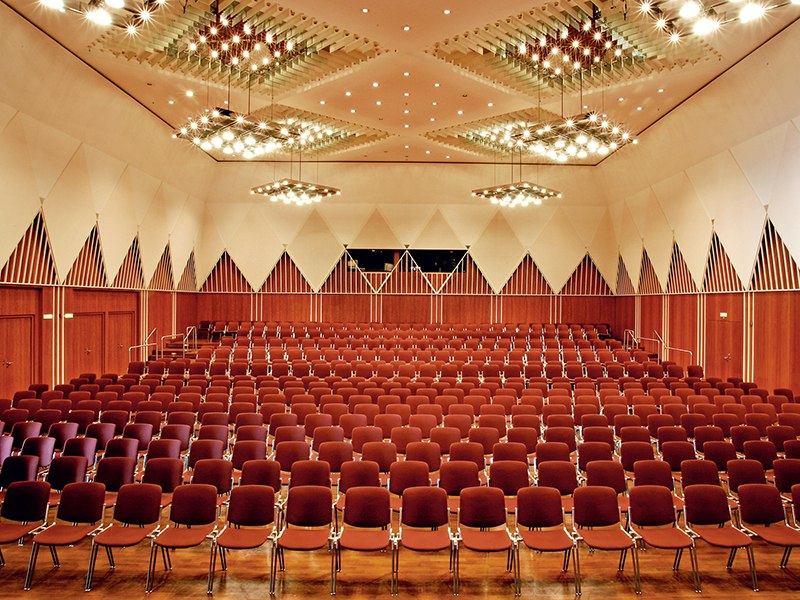 Large conference room with red chairs, modern lighting and geometric wall patterns in the Kronenzentrum Bietigheim-Bissingen., © Kronenzentrum Bietigheim-Bissingen