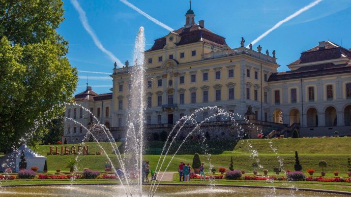 Das Residenzschloss Ludwigsburg mit einem großen Springbrunnen im Vordergrund. Der Himmel ist blau mit Kondensstreifen, umgeben von gepflegten Gärten., © Tourismus & Events Ludwigsburg Das Residenzschloss Ludwigsburg mit einem großen Springbrunnen im Vordergrund. Der Himmel ist blau mit Kondensstreifen, umgeben von gepflegten Gärten., © Tourismus & Events Ludwigsburg
