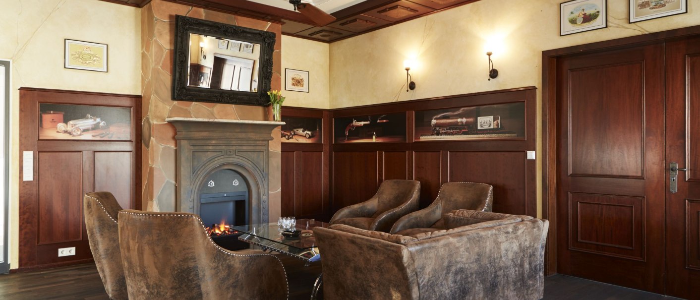 Elegant room with fireplace, leather armchairs and wooden walls. There are pictures on the walls and a large mirror above the fireplace., &copy; MW Region Stuttgart