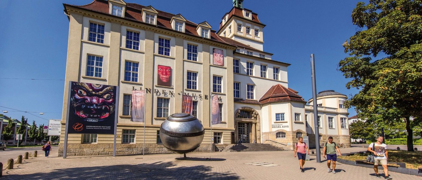 Das Linden-Museum in Stuttgart bei sonnigem Wetter. Vor dem Gebäude steht eine große Metallkugel, Passanten gehen vorbei., © Stuttgart-Marketing GmbH Achim Mende