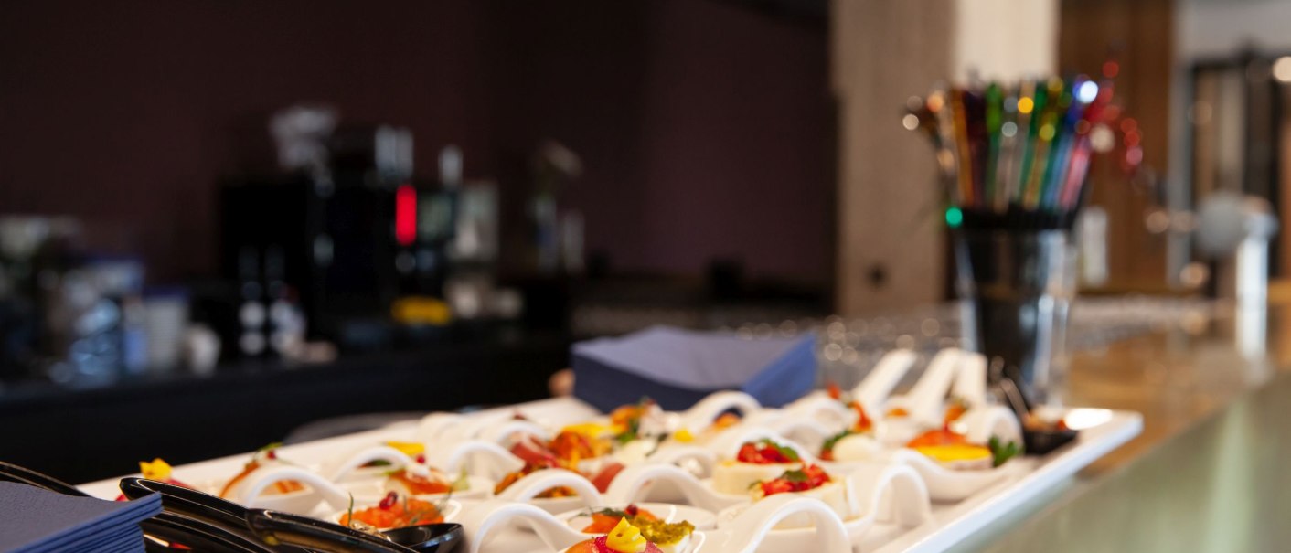 A tray with decorative canapés stands on a table in a modern room. Blurred details of a bar can be seen in the background., © Stefan Baraniecki A tray with decorative canapés stands on a table in a modern room. Blurred details of a bar can be seen in the background., © Stefan Baraniecki