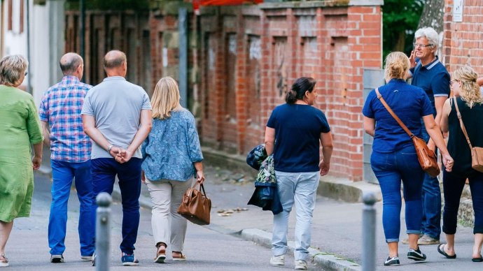 Gruppe von Menschen spaziert entlang einer Backsteinmauer in der Stadt., © Thomas Niedermüller