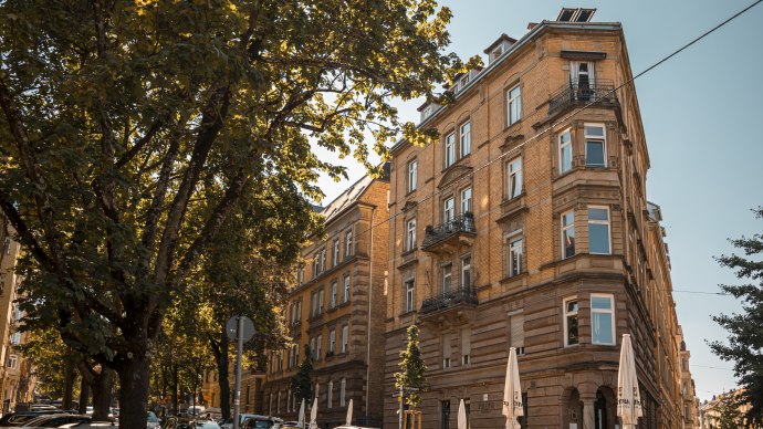 Historisches Gebäude an einer Straßenecke, umgeben von Bäumen und geparkten Autos. Sonniger Tag mit klarem Himmel., © SMG Stuttgart Marketing GmbH - Sarah Schmid