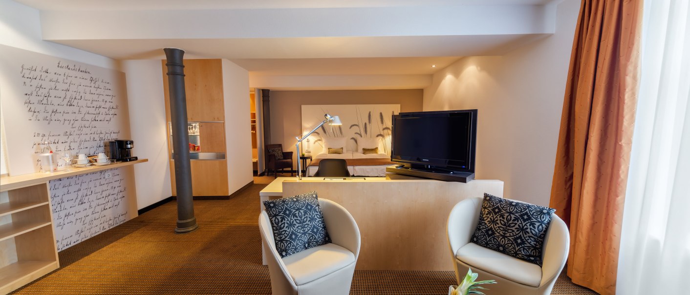 Modern hotel room with seating area, TV, desk and fruit plate. Bright curtains and stylish furnishings., &copy; nestor Hotel Ludwigsburg