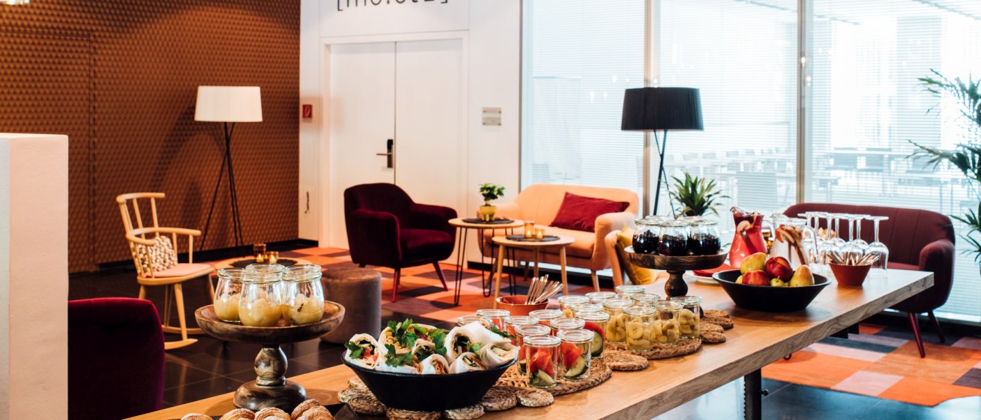 Modernes Foyer mit gemütlichen Sitzgelegenheiten, Snacks und Getränken auf einem Tisch. Helle Beleuchtung und stilvolle Dekoration., © VHE Mo.Stuttgart