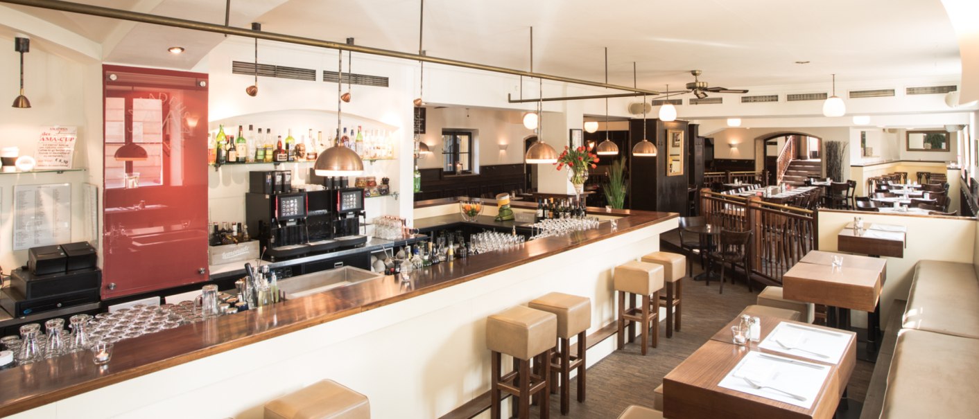 Stilvolles Restaurant mit Bar, Holzmöbeln und gedeckten Tischen. Helle Beleuchtung und gemütliche Atmosphäre., © Amadeus, Stuttgart Stilvolles Restaurant mit Bar, Holzmöbeln und gedeckten Tischen. Helle Beleuchtung und gemütliche Atmosphäre., © Amadeus, Stuttgart