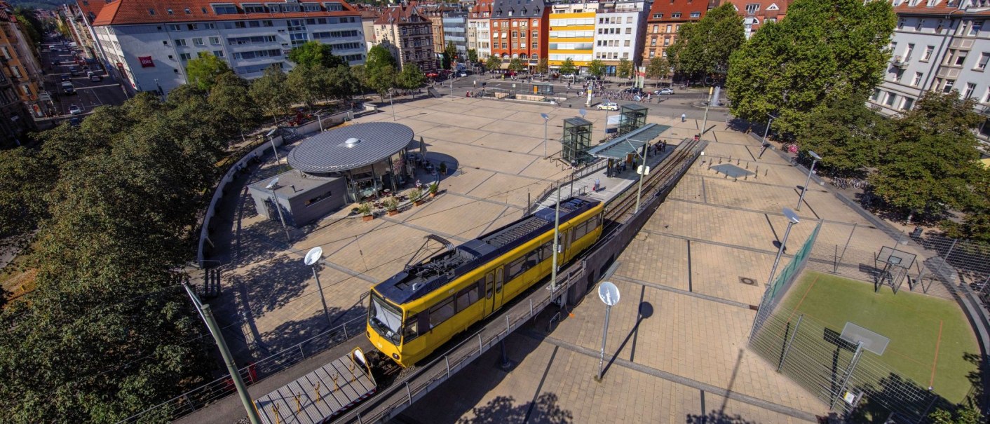 Luftaufnahme des Marienplatzes mit gelber Straßenbahn, umliegenden Gebäuden und Bäumen. Ein kleiner Sportplatz ist ebenfalls zu sehen., © Achim Mende
