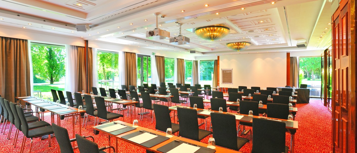 A bright conference room with red carpets, tables and chairs, large windows and modern lighting at the Schlosshotel Monrepos., © Schlosshotel Monrepos A bright conference room with red carpets, tables and chairs, large windows and modern lighting at the Schlosshotel Monrepos., © Schlosshotel Monrepos