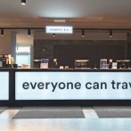 Moderne Rezeption im a&o Stuttgart City mit beleuchtetem Tresen und dem Schriftzug 'everyone can travel'., &copy; a&o Hostels