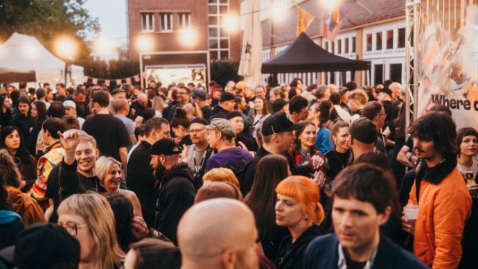 Gro&szlig;e Menschenmenge bei einem Outdoor-Event mit festlicher Beleuchtung und verschiedenen St&auml;nden im Hintergrund., &copy; Ilkay Karakurt