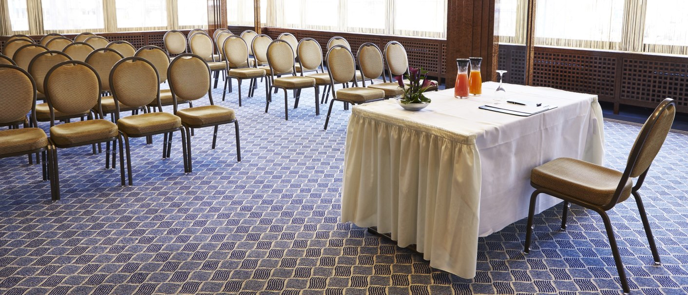 A conference room with rows of chairs and a table with drinks on it. Large windows let in plenty of light., © Steigenberger Hotels AG